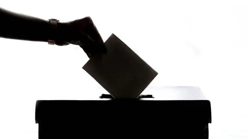 Silhouette d'une main glissant un bulletin dans une urne