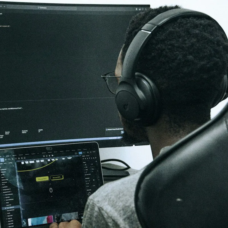 Un développeur au casque devant ses écrans de code