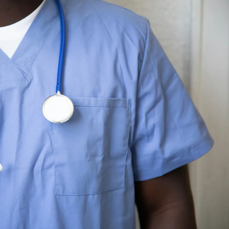 Un soignant en tenue bleue, stéthoscope autour du cou