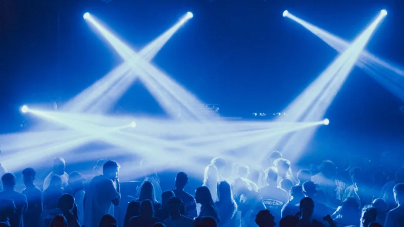 Une foule danse sous des faisceaux de lumière bleue