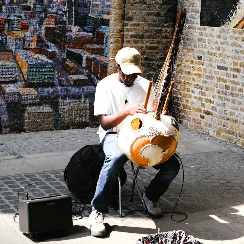 Un musicien joue de la kora devant un mur peint