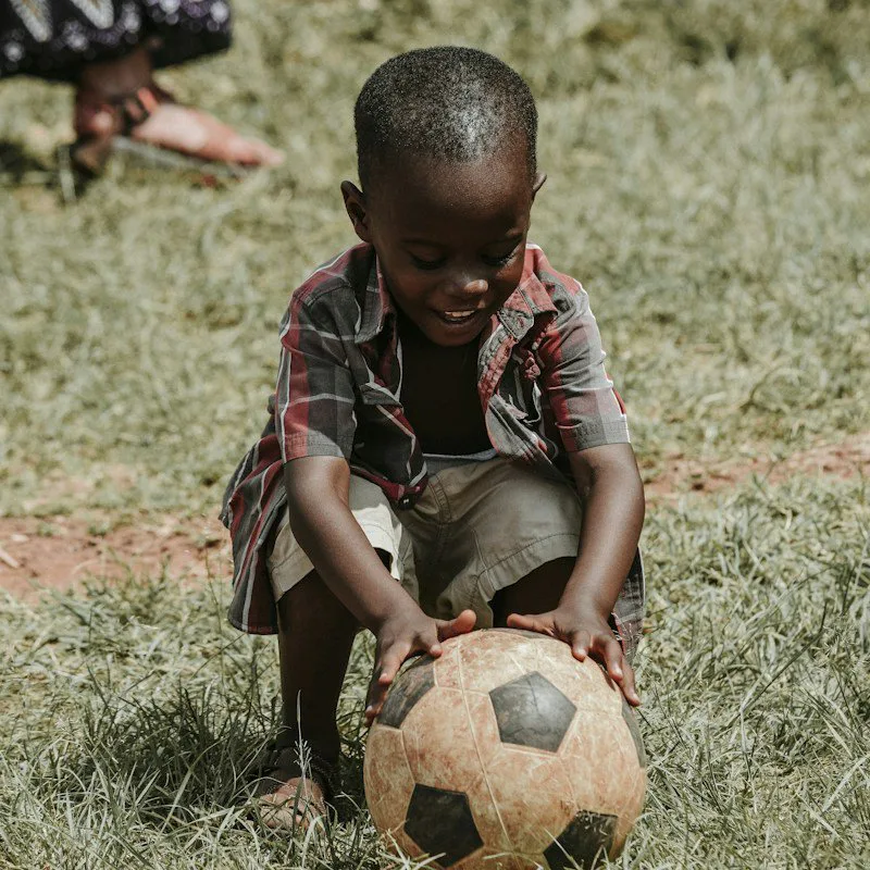 Un garçon souriant, un ballon de football entre les mains