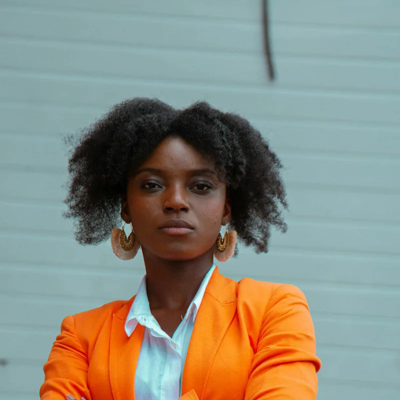 Une femme en veste orange, regard assuré